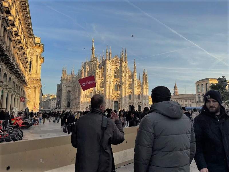 tour guide with people at piazza del duomo at milan cathedral