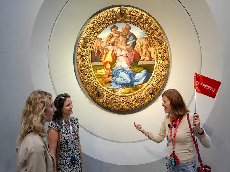 A pair of women in front of Michelangelo's Holy Family in the Uffizi Gallery with a guide from The Tour Guy.