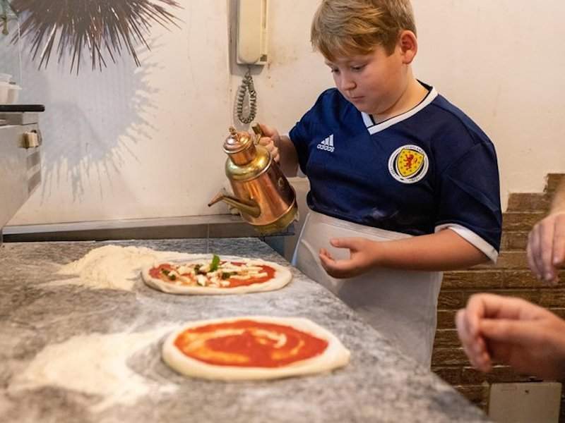 boy pouring oil on pizza