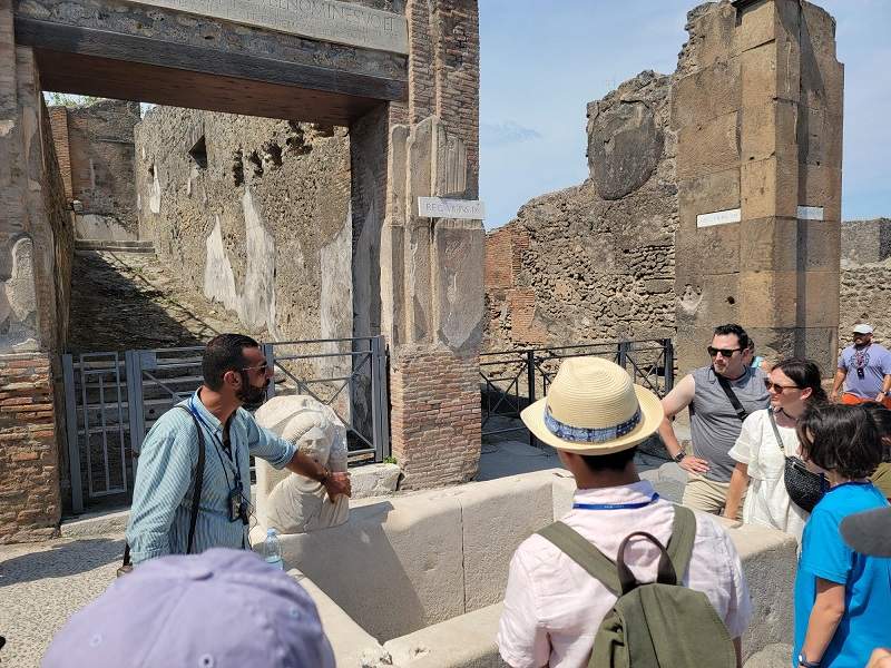 A group of tourists looking at the Thermal Baths of Pompeii with their guide from The Tour Guy.