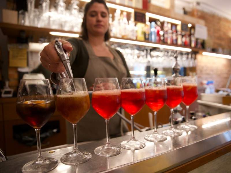 A bartender pouring multiple Spritz in a bar in Venice.