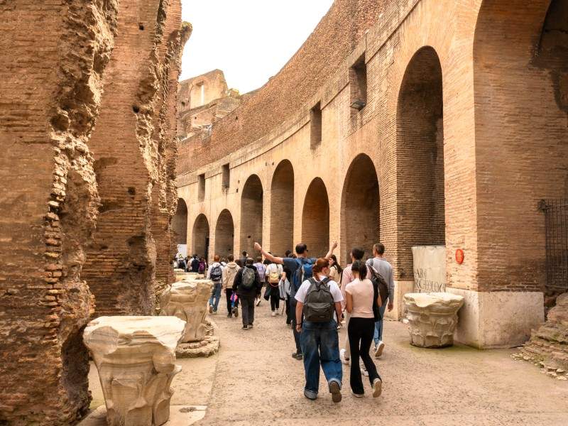 A group of tourists walking through the 1st level of the Colosseum.