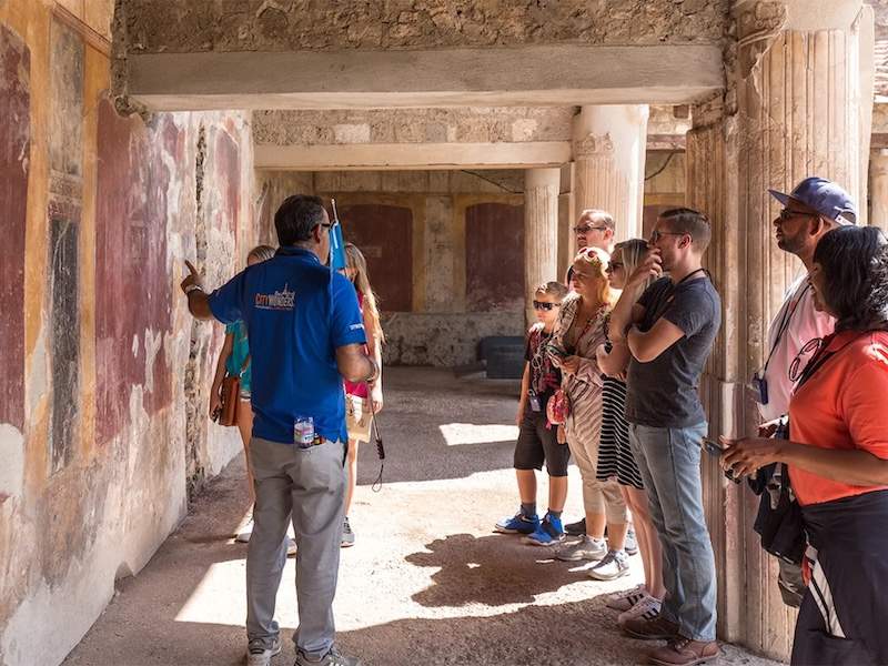 Guide in Pompeii showing the murals to a group