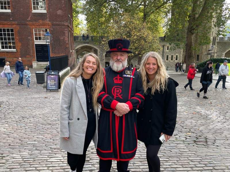 Two tourists taking a picture with a Tower of London Beefeater while on tour with The Tour Guy.