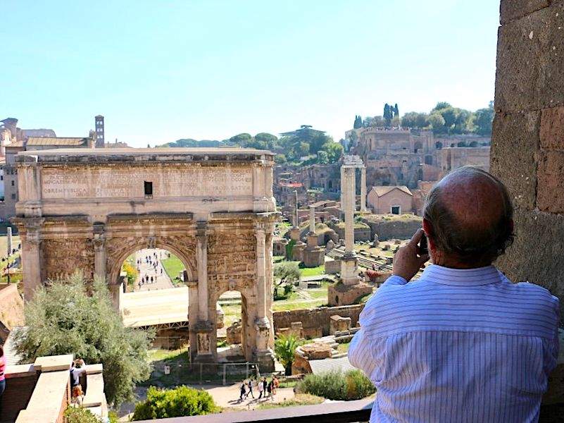 A man looking at the Arch of Titus in the Roman Forum.