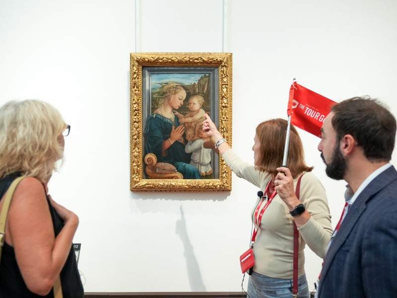 Two tourists in front of the Madonna and Child painting at the Uffizi Gallery while on tour with The Tour Guy.