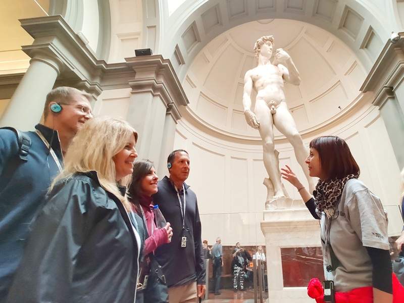 A group of tourists in front of the Statue of David while listening to their guide from The Tour Guy.