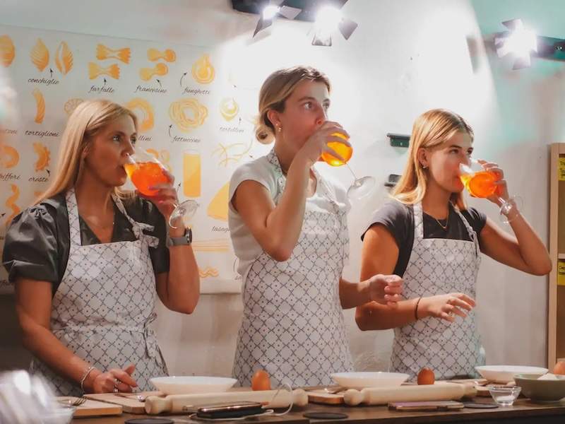 A group of women in aprons drinking spritz at a cooking class