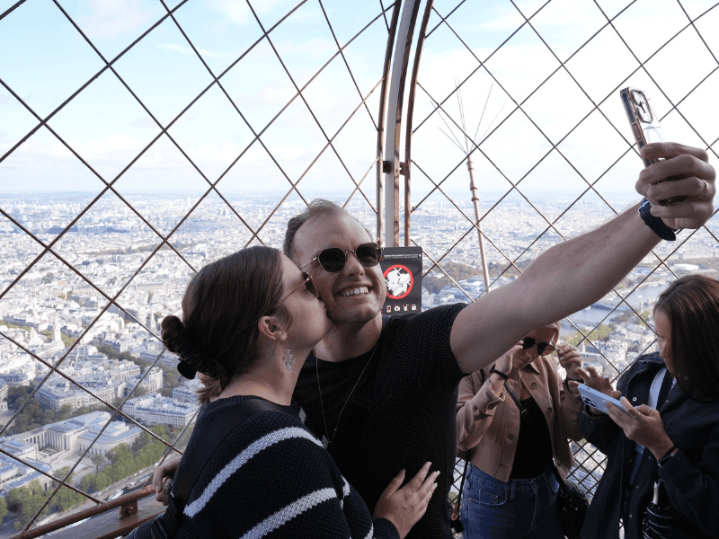 A couple taking a selfie while visiting the 2nd level of the Eiffel Tower.