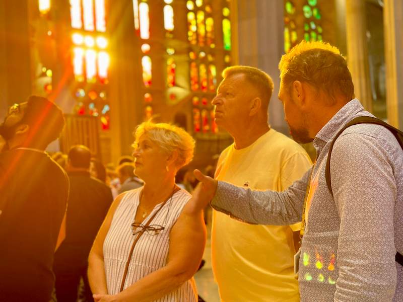 A pair of tourists inside the Sagrada Familia during Golden Hour listening to their guide from The Tour Guy.