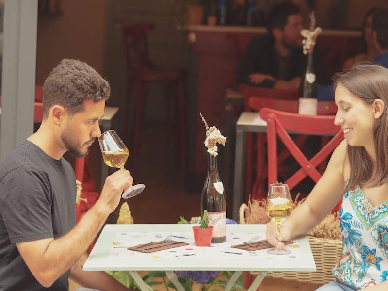 Man and woman sitting outside and tasting a glass of wine