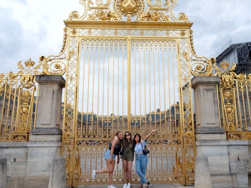 A group of tourist taking a picture in front of Gates of Versalilles while on tour with The Tour Guy.