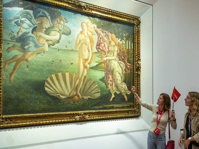 A woman looking at the Birth of Venus in the Uffizi Gallery with a guide from The Tour Guy.