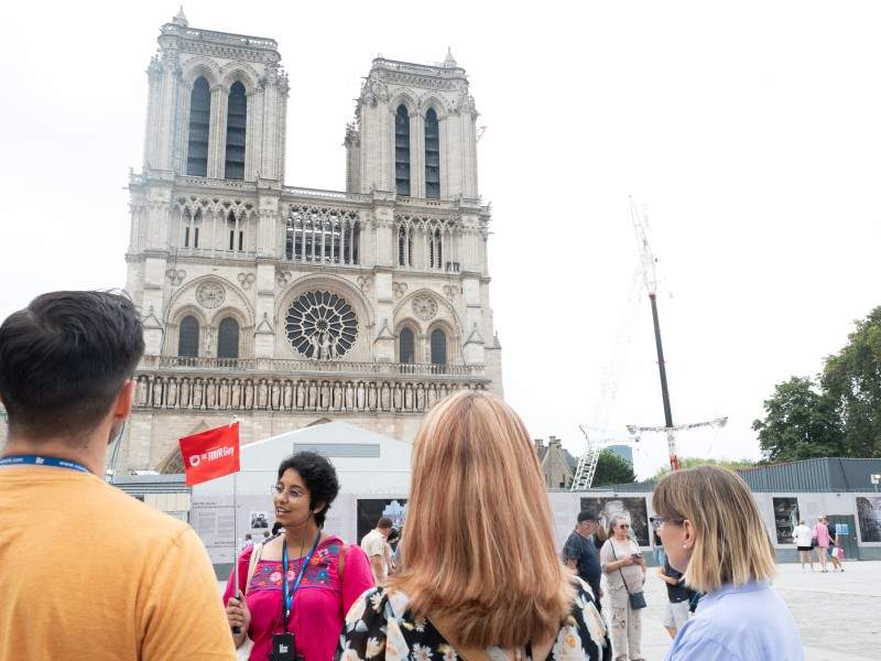 An image of tourists outside of Notre Dame in Paris with a tour guide.