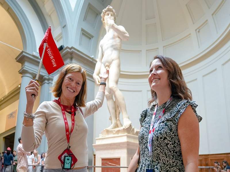 A woman in front of the Statue of David in the Accademia Gallery with her guide from The Tour Guy.