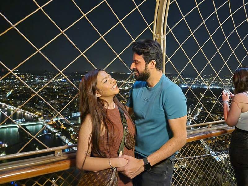 A couple on the Eiffel Tower's 2nd level at night.