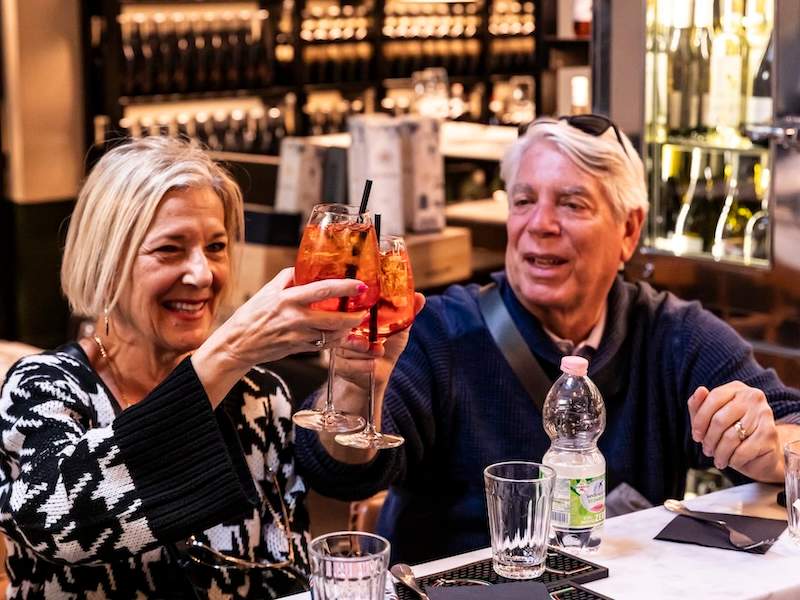 A person and person holding glasses of drinks and cheering