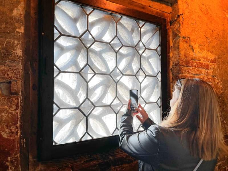 A woman taking a picture of a window inside the Doge's Palace.