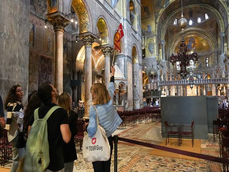 A woman taking a picture of the golden archways inside St. Mark's Basilica.