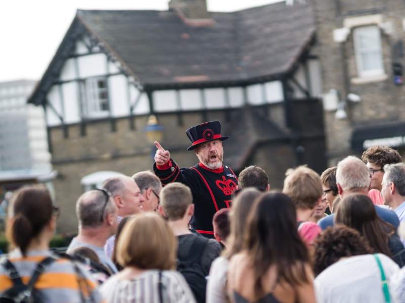 An image of a Tower of London Beefeater speaking to a crowd.