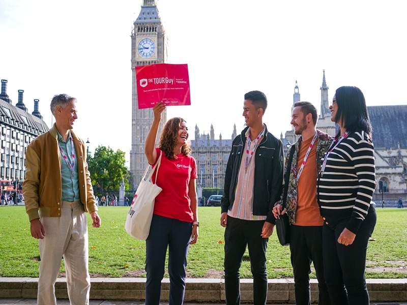 A group of tourists in Parliament Square with Big Ben in the background speaking with their guide from The Tour Guy.