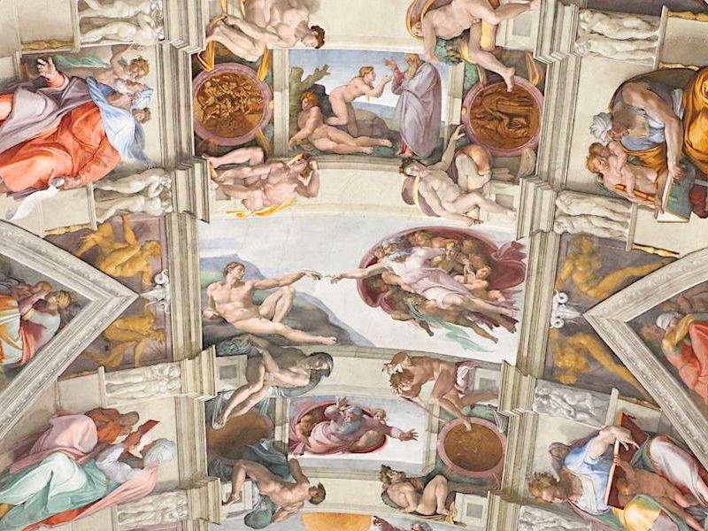 An image of The Creation of Adam inside the Sistine Chapel.