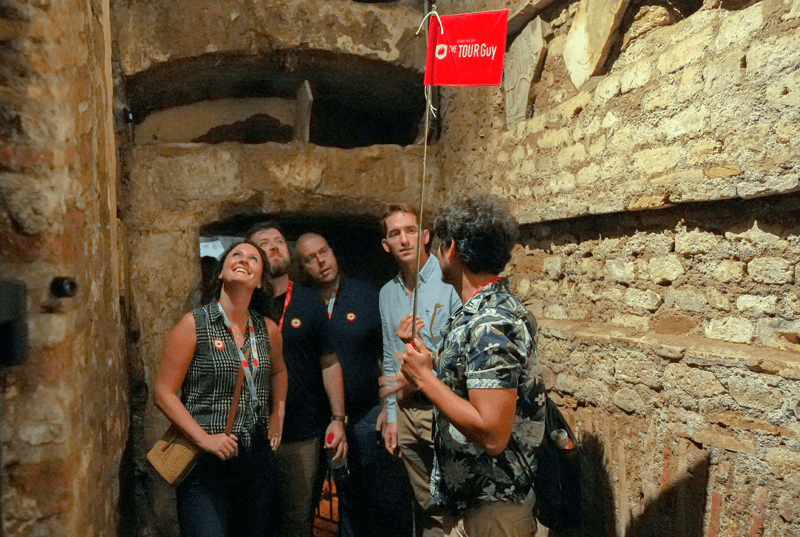 A group of tourists inside the catacombs in Rome with a guide from The Tour Guy.