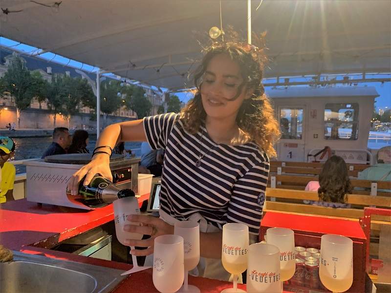 A bartender on a Vedette de Paris pouring champagne.