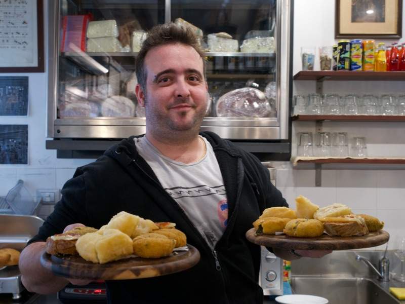 A man serving Venetian snacks in a restaurant.