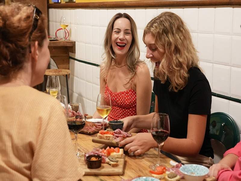 Women sitting at a table in a restaurant in Florence enjoying various Italian meats and wine.