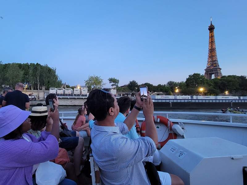 A group of tourists on a Seine River Cruise taking photos of the Eiffel Tower 