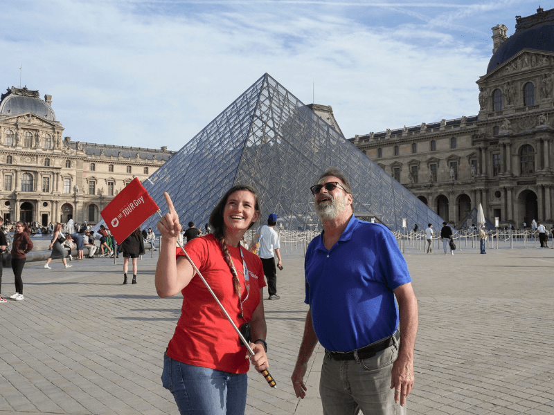 A man in front of the Louvre Pyramid with a guide from The Tour Guy.