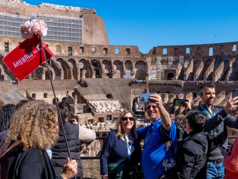 A group of tourists taking a selfie at the Colosseum standing next to their guide from The Tour Guy.