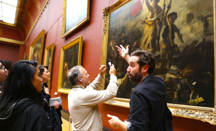 tour guide showing visitors famous paintings in the Louvre
