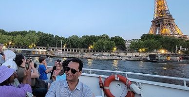People taking photos of the Eiffel tour from a boat.
