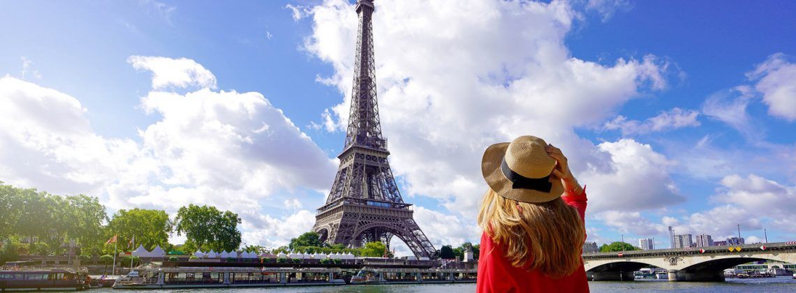 Women standing in front of the Eiffel Tower during the day.