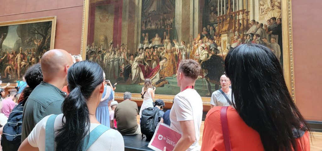 people and guide looking at coronation of napoleon