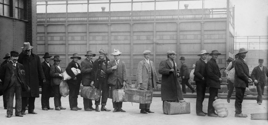 black and white photo of immigrants lining up at Ellis Island.