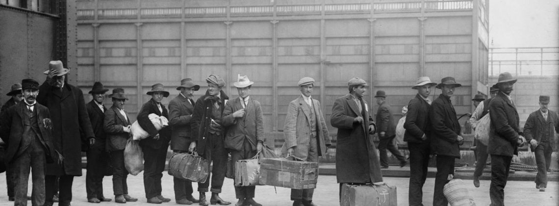 black and white photo of immigrants lining up at Ellis Island.