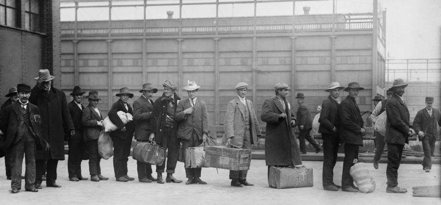 black and white photo of immigrants lining up at Ellis Island.