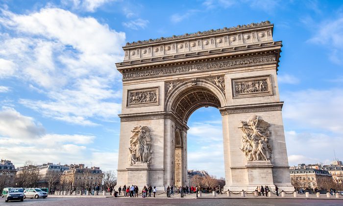 people standing under the arc de triomphe monument in Paris
