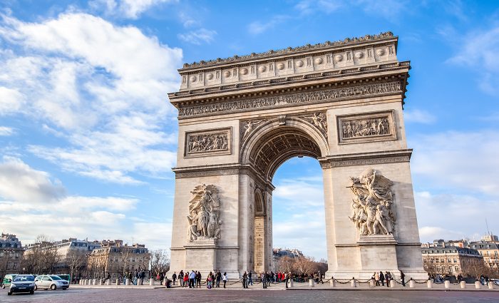 people standing under the arc de triomphe monument in Paris
