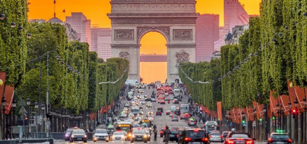 Street with cars leading up to the Arc de Triomphe.