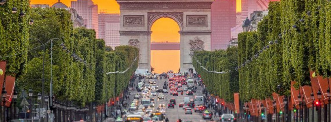 Street with cars leading up to the Arc de Triomphe.