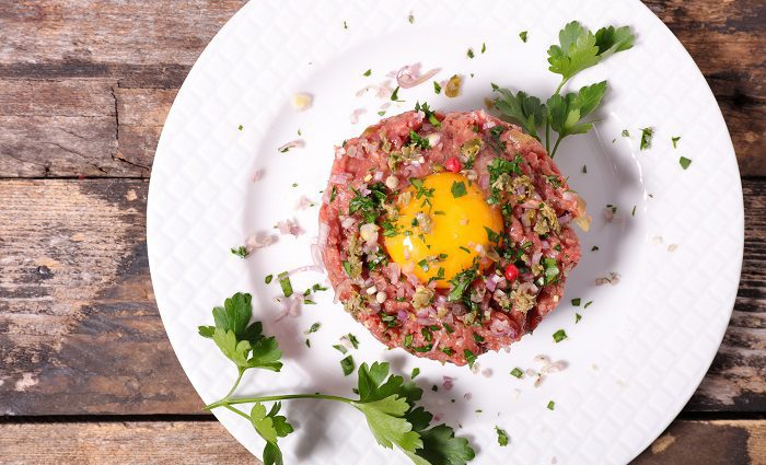 plate of steak tartare with egg and herbs