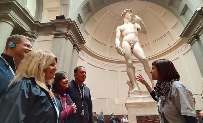 People on a Florence walking tour standing in front of the statue of David in the Accademia Gallery.