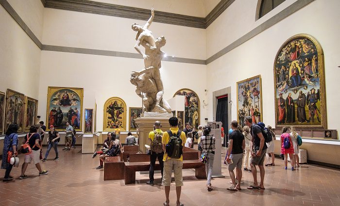 Visitors of the Accademia Gallery, Florence, in the Hall of Colossus looking up at the centerpiece sculpture, the Rape of the Sabine.