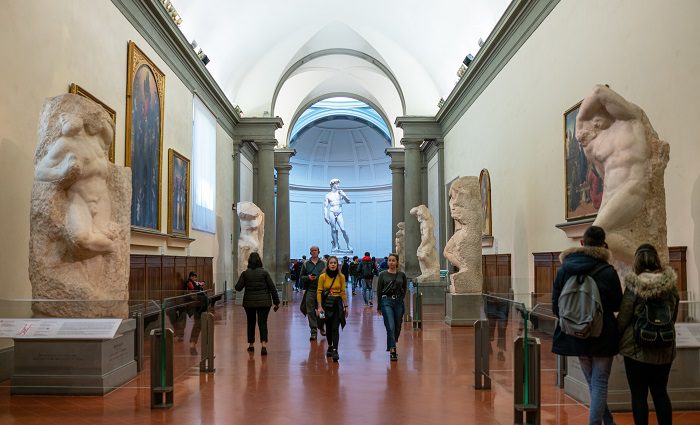 Visitors walking throught the Accademia Gallery's Hall of Prisoners with unfinished sculptures leading up to the David statue.