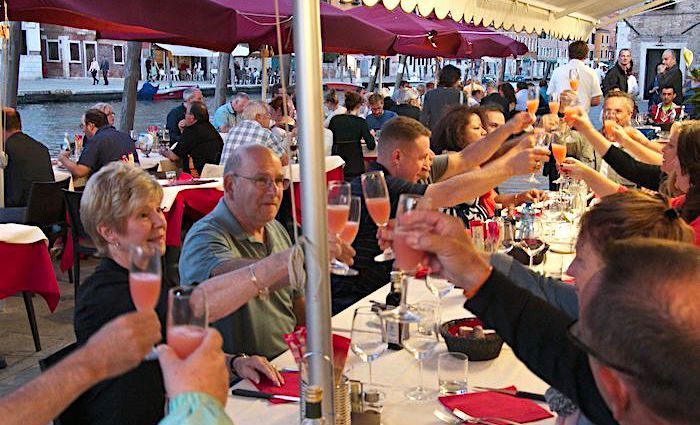 A group of people saying cheers in a restaurant near St. Mark's Basilica in Venice