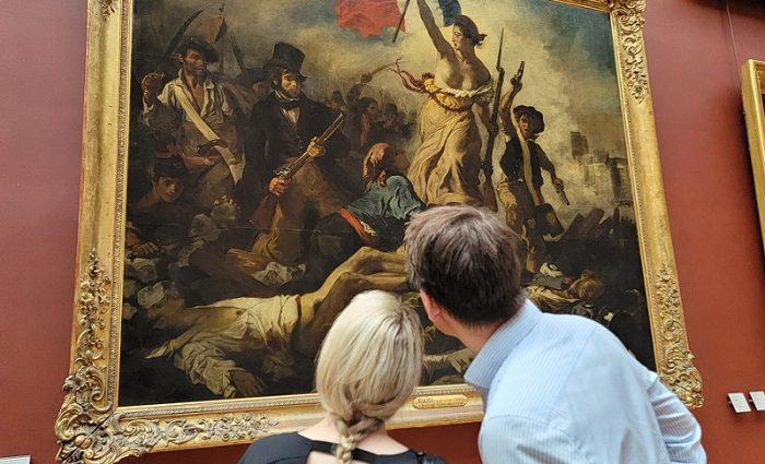 Visitors on a tour seeing the "Liberty leading the people" painting in the Louvre